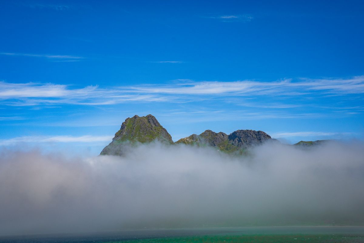 Blekktinden peaking from the layer of ocean fog in Lofoten